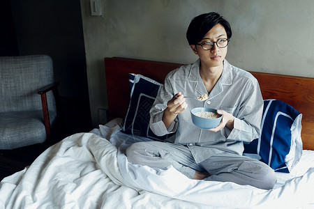 坐在床上吃早餐的男人图片