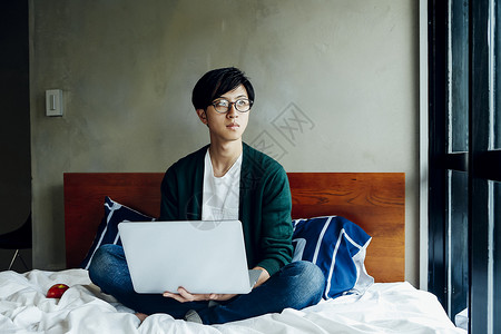 坐在床上使用电脑的男人图片
