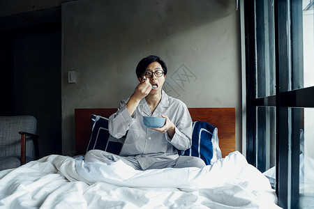 坐在床上吃早餐的男人图片