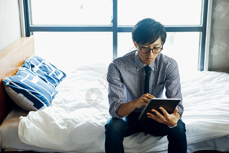 坐在床边看平板电脑的男人图片