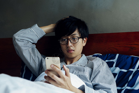 躺在床上玩手机的男人图片