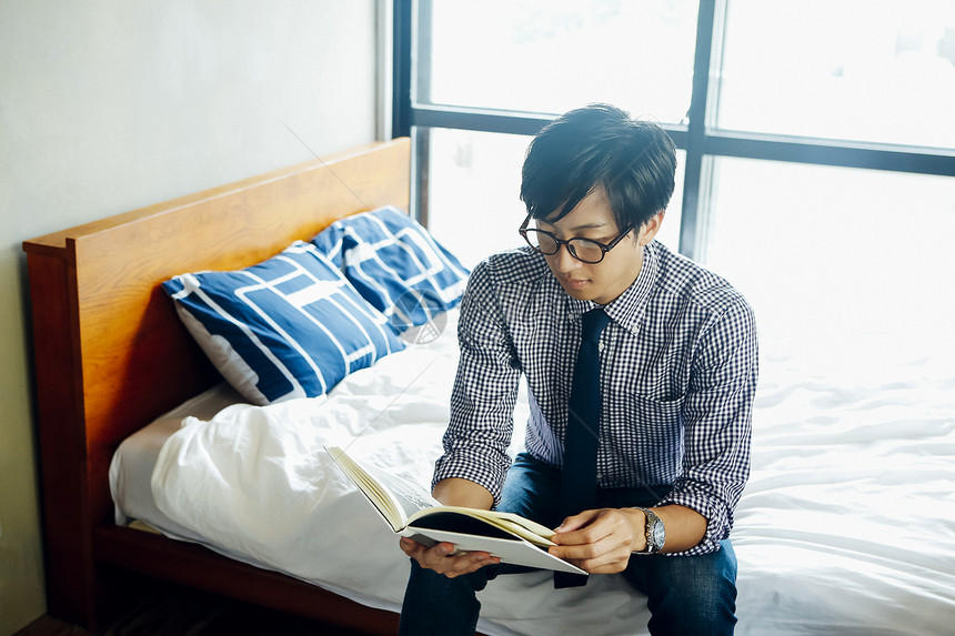 男人坐在床上看书图片