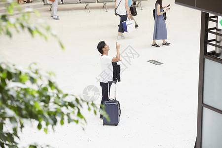 在机场拖着行李箱的男性看指示牌图片