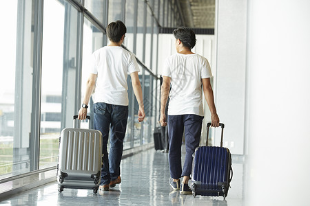 两个男子拖着行李走在机场大厅图片