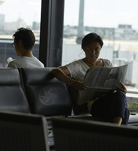 在机场候机厅看报等候的2个男性图片
