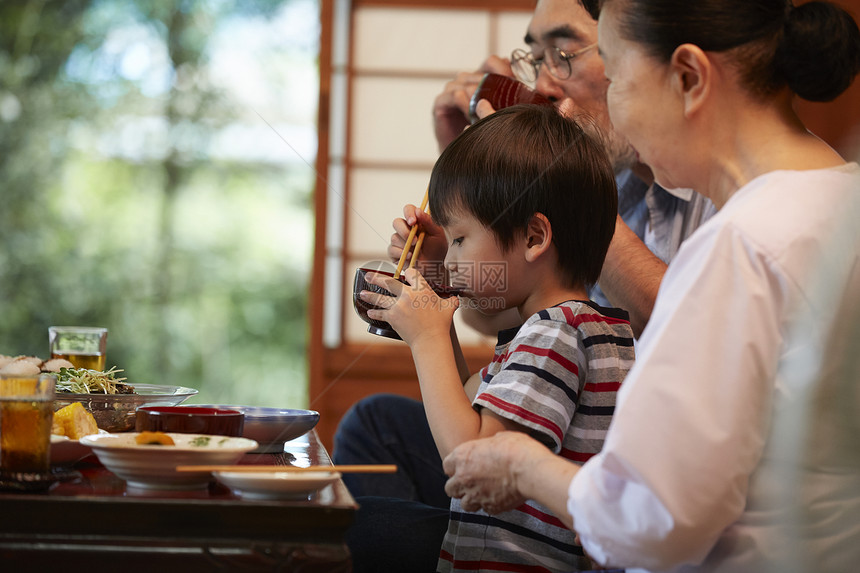 日式房屋餐桌边吃饭的3人图片