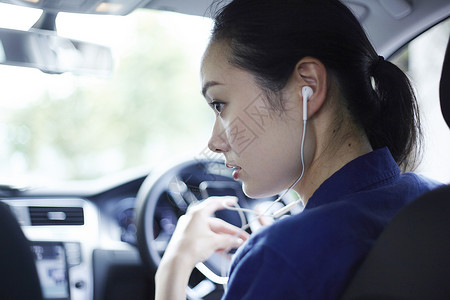 汽车驾驶位上戴耳机的女白领图片
