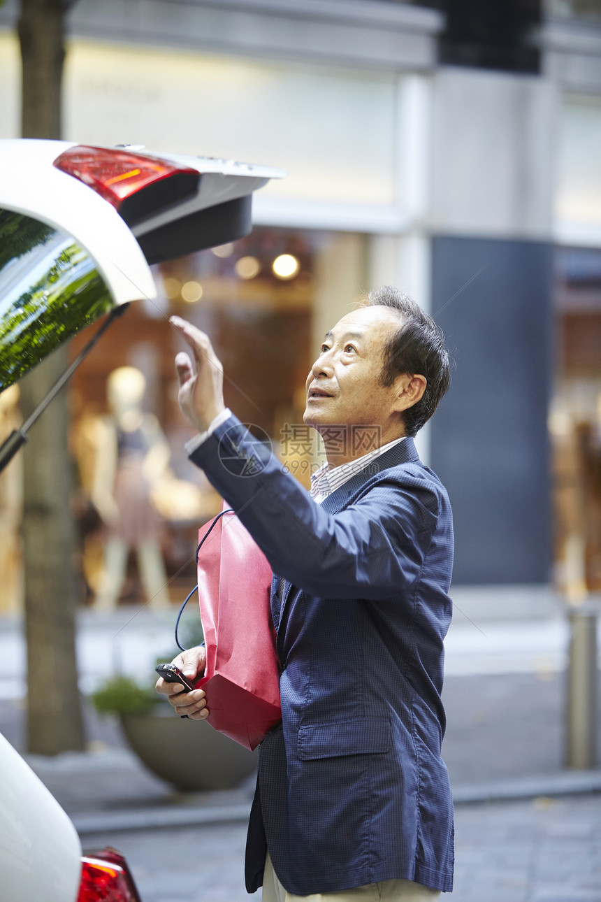 在街上年长男子准备关闭后备箱图片