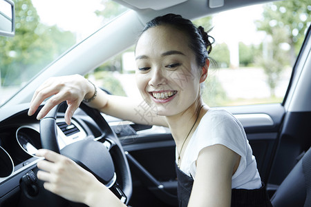 汽车座位上抱着方向盘的年轻女性图片