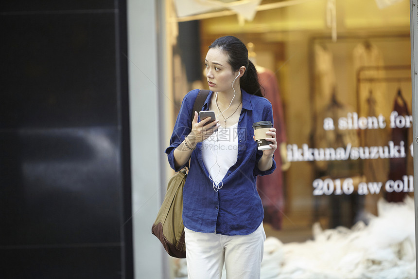 时髦女白领拿着咖啡走在街上打电话图片
