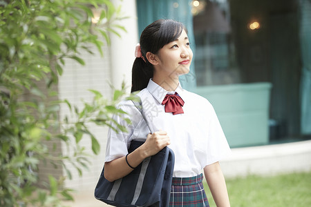 彩带袋子素材在房子前面的穿校服的女孩背景