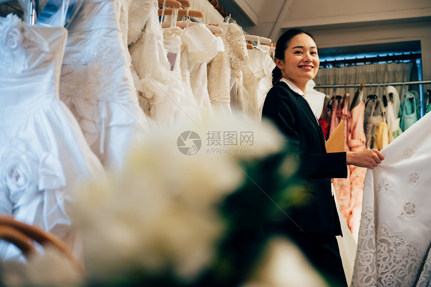 婚纱店内整理婚纱的婚礼策划师形象图片