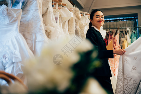 婚纱店内整理婚纱的婚礼策划师形象背景图片