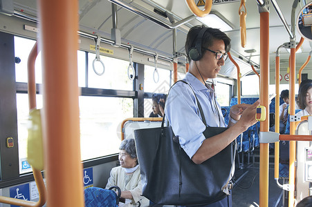  戴耳机坐公交车的男性图片