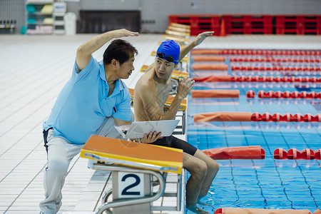 泳池边指导训练的游泳运动员和教练图片