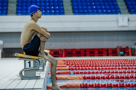 坐在泳池边思考的游泳运动员背景图片