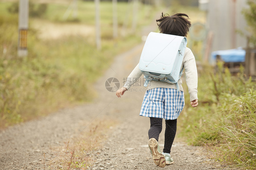 田野里背着书包奔跑的儿童图片