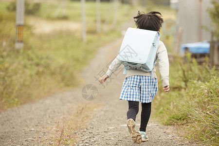 田野里背着书包奔跑的儿童图片