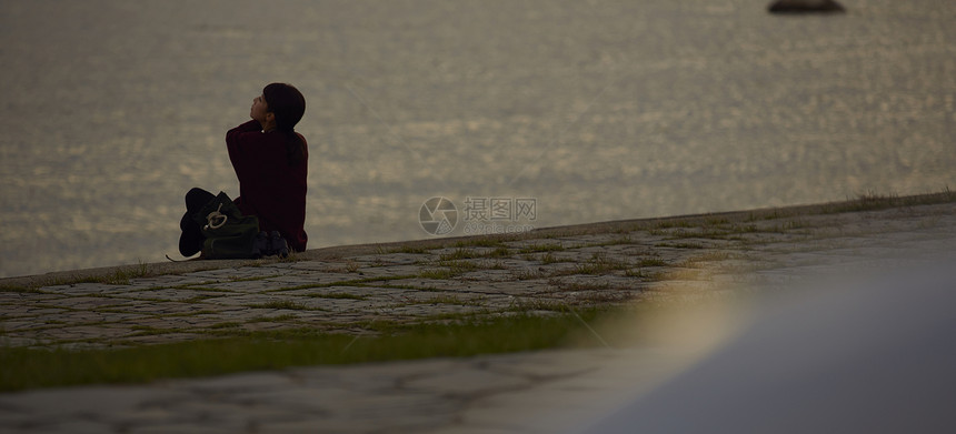 黄昏年轻女人坐在海边图片