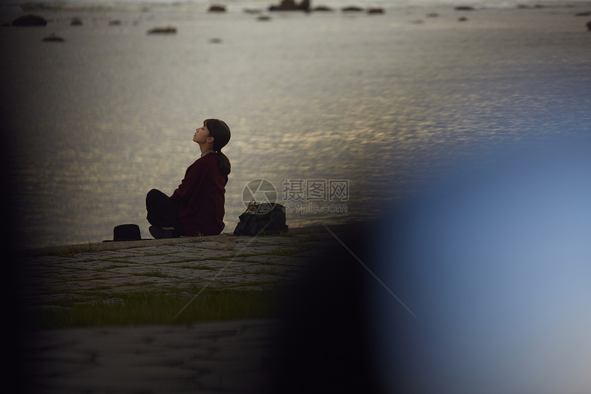 黄昏年轻女人坐在海边图片