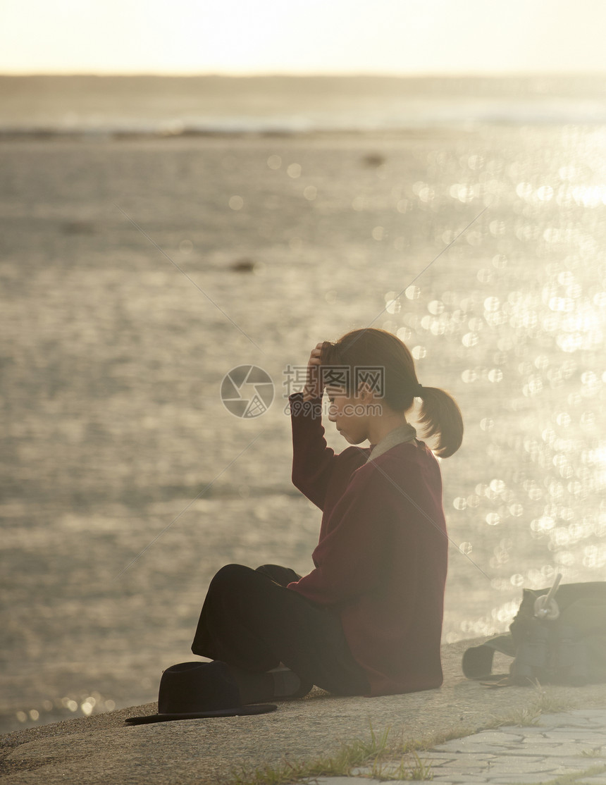 黄昏夕阳下年轻女人坐在海边图片