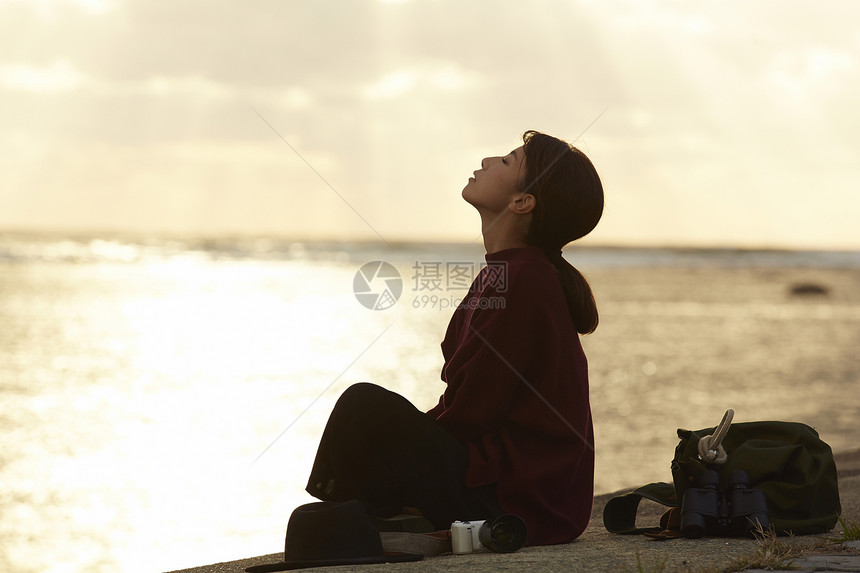 黄昏夕阳下年轻女人坐在海边图片