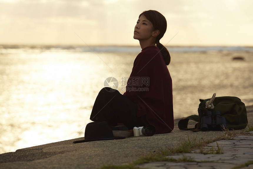 黄昏夕阳下年轻女人坐在海边图片