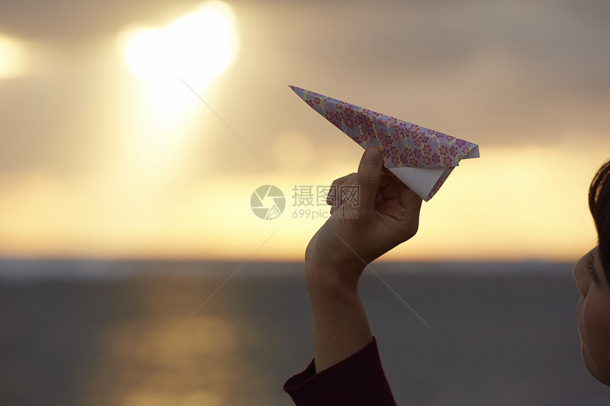 女人在夕阳下手拿纸飞机图片