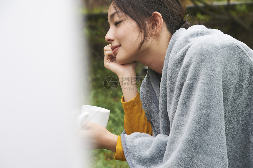 拿着杯子在草地上撑着头的女人图片