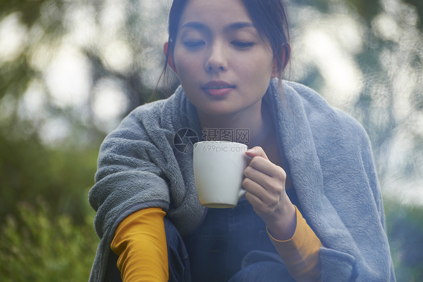 披着毯子拿着杯子的女人图片