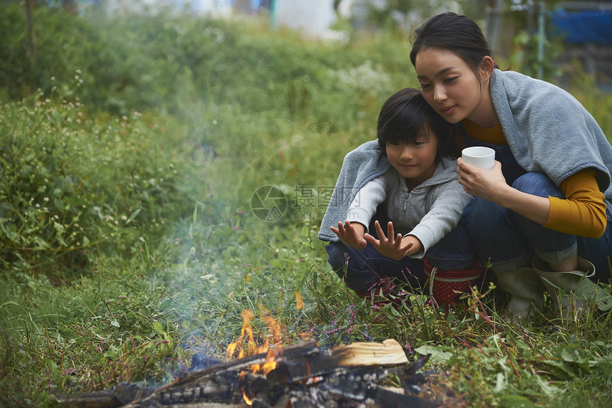母亲和孩子在户外烤篝火图片