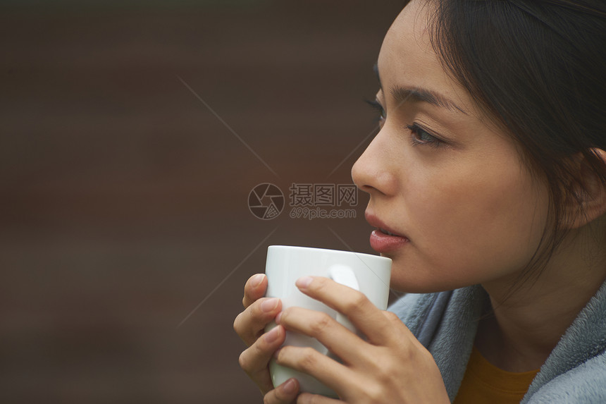 少披着毛毯喝咖啡的女性图片