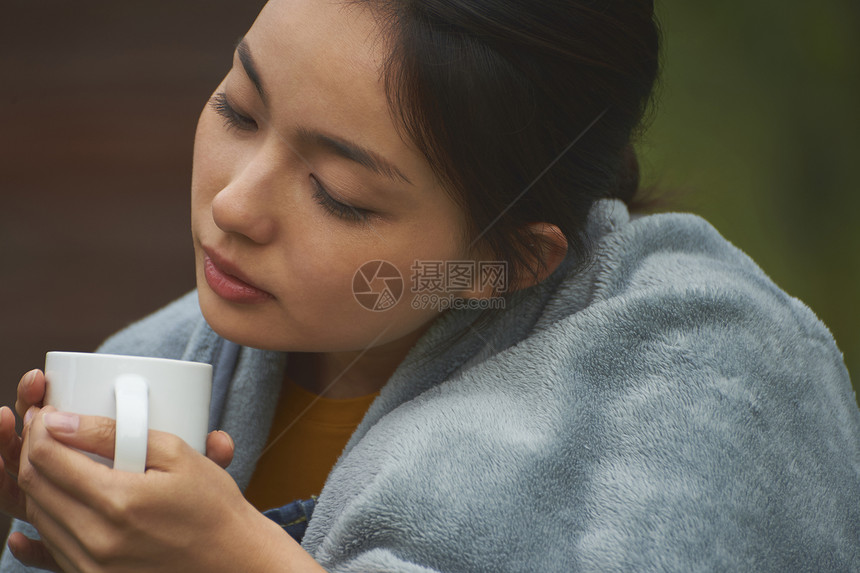 披着毛毯喝咖啡的女性图片