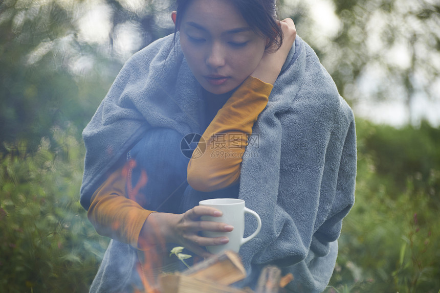 蹲在篝火前取暖的女性图片
