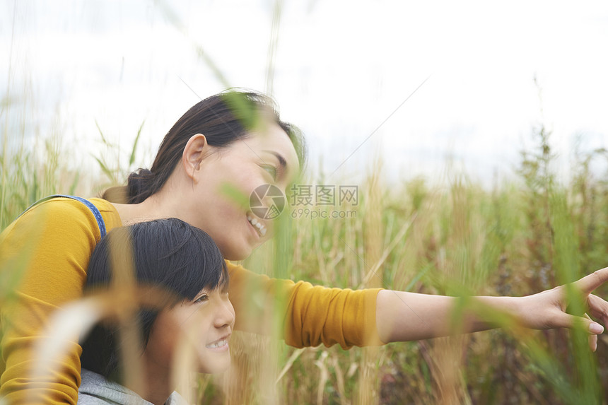 站在户外草丛里看向远方的母子二人图片