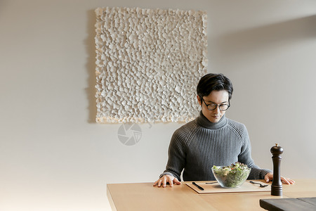 穿着高领毛衣的男人坐在客厅吃轻食图片