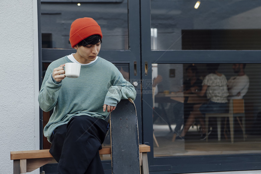 年轻人端着茶杯坐在门口边图片