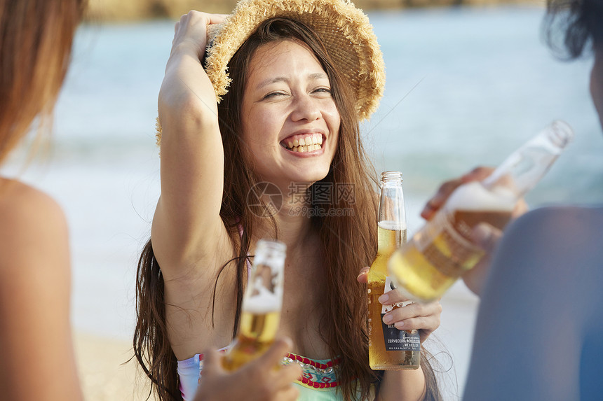 在夏威夷海边开心喝啤酒聊天的年轻人图片