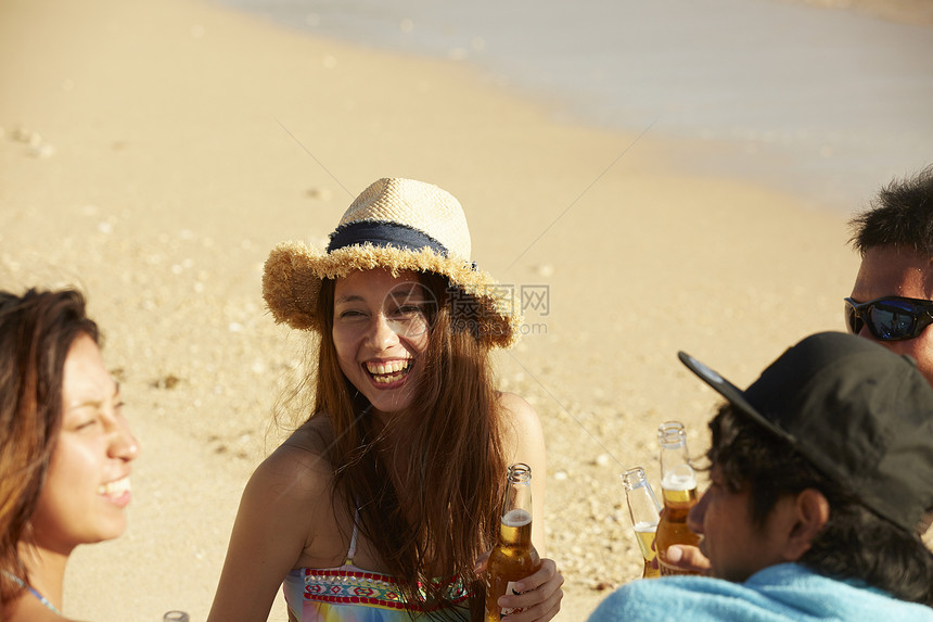 在夏威夷海边开心喝啤酒聊天的年轻人图片