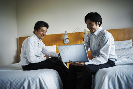高档床两位商务男子在酒店房间谈工作背景
