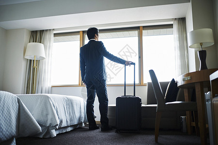 商务男子拎着行李箱入住酒店背景图片