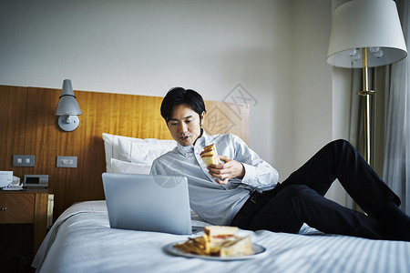 商务人士放松的在酒店床上吃早饭图片
