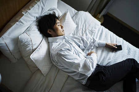 早晨在酒店床上休息的商务男子图片