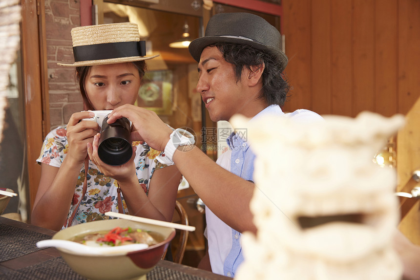 夏天带草帽的游客吃拉面前拍照图片