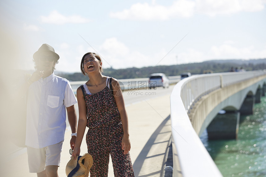 在海边的桥上散步的情侣图片