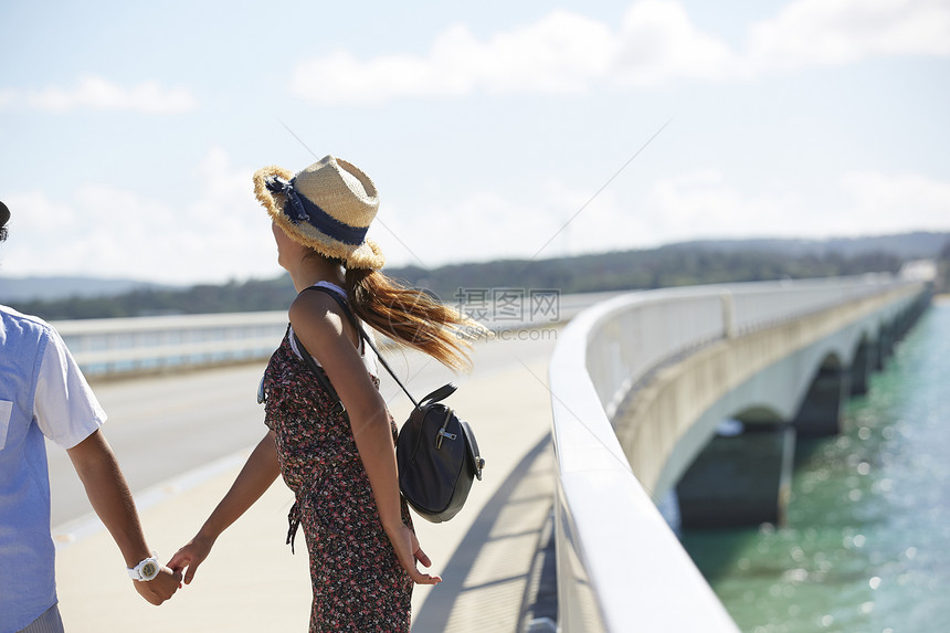 情侣手牵着手走在海上大桥上图片
