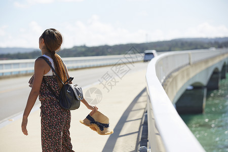 旅途中的女性走在海面大桥上高清图片