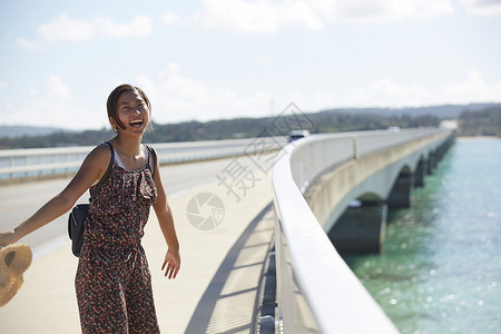 旅途中情侣手牵着手走在海上大桥上高清图片