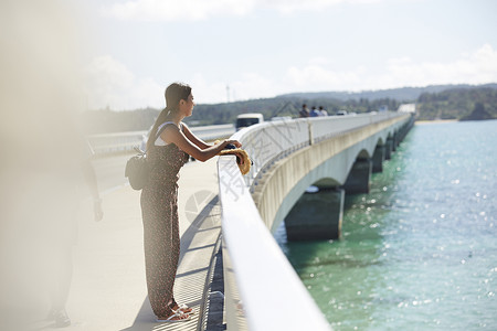 旅途中的女性走在海面大桥上看风景高清图片