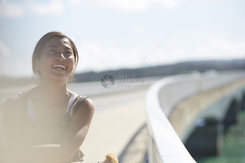 旅途中带着草帽的女性走在海面大桥上大笑图片